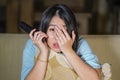 Young beautiful and scared Asian Chinese teenager woman in fear watching horror scary movie at home sofa couch eating popcorn bowl Royalty Free Stock Photo