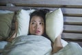 Young beautiful scared Asian Chinese woman lying awake in bed sleepless covering head with pillow suffering nightmare insomnia dis Royalty Free Stock Photo