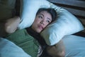 Young beautiful scared Asian Chinese woman lying awake in bed sleepless covering head with pillow suffering nightmare insomnia dis Royalty Free Stock Photo