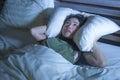 Young beautiful scared Asian Chinese woman lying awake in bed sleepless covering head with pillow suffering nightmare insomnia dis Royalty Free Stock Photo