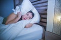 Young beautiful scared Asian Chinese woman lying awake in bed sleepless covering head with pillow suffering nightmare insomnia dis Royalty Free Stock Photo