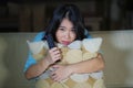 Young beautiful and scared Asian Japanese teenager woman in fear watching horror scary movie at home sofa couch eating popcorn Royalty Free Stock Photo