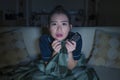 Young beautiful scared and frightened Asian Japanese woman watching horror scary movie or thriller eating popcorn in fear face Royalty Free Stock Photo