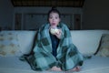 Young beautiful scared and frightened Asian Korean woman watching horror scary movie or thriller eating popcorn in fear face Royalty Free Stock Photo