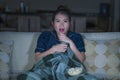 Young beautiful scared and frightened Asian Korean woman watching horror scary movie or thriller eating popcorn in fear face Royalty Free Stock Photo