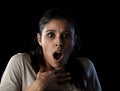 Young beautiful scared Spanish woman in shock and surprise face expression isolated on black Royalty Free Stock Photo