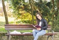 Young beautiful school or college girl with eyeglasses sitting on the bench in the park reading the books and study for exam Royalty Free Stock Photo