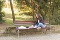 Young beautiful school or college girl with eyeglasses sitting on the bench in the park reading the books and study for exam Royalty Free Stock Photo