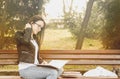 Young beautiful school or college girl with glasses sitting on the bench in the park reading the books and study for exam Royalty Free Stock Photo