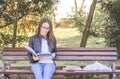 Young beautiful school or college girl with glasses sitting on the bench in the park reading the books and study for exam Royalty Free Stock Photo