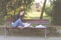 Young beautiful school or college girl with glasses sitting on the bench in the park reading the books and study for exam Royalty Free Stock Photo