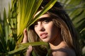 Young beautiful sensual sexy woman with healthy skin of face and palm leaves. Closeup fresh face of attractive girl Royalty Free Stock Photo