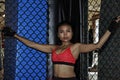 Beautiful and Asian fighter woman in fighting gloves and sport clothes inside MMA cage posing cool Royalty Free Stock Photo