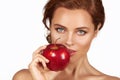 Young beautiful girl with dark curly hair, bare shoulders and neck, holding big red apple to enjoy the taste and are dieting, Royalty Free Stock Photo