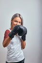 Young beautiful sexy woman boxer posing with black boxing gloves in her hands on a gray background. Copy space, gray Royalty Free Stock Photo