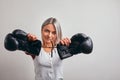 Young beautiful sexy woman boxer posing with black boxing gloves in her hands on a gray background. Copy space, gray Royalty Free Stock Photo