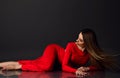 Young beautiful sexy woman with long hair in red maxi dress barefoot lying on floor showing perfect body lines and Royalty Free Stock Photo