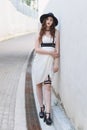 Young beautiful woman wearing trendy outfit, white dress, black hat and leather swordbelt. Longhaired brunette Royalty Free Stock Photo