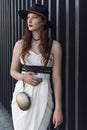 Young beautiful woman wearing trendy outfit, white dress, black hat and leather swordbelt. Longhaired brunette Royalty Free Stock Photo