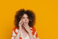 Young beautiful shocked curly woman talking phone covering her mouth Royalty Free Stock Photo