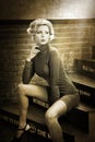 Young beautiful short hair blonde woman in turtle neck tight short dress sitting on stairs, black and white photo Royalty Free Stock Photo