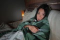 Young beautiful sick and exhausted Asian Chinese woman suffering cold and flu holding thermometer having temperature lying on bed Royalty Free Stock Photo