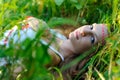 Young beautiful Slavic girl with long hair and Slavic ethnic attire lies in the grass in a summer forest Royalty Free Stock Photo