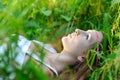 Young beautiful Slavic girl with long hair and Slavic ethnic attire lies in the grass in a summer forest Royalty Free Stock Photo