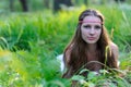 Young beautiful Slavic girl with long hair and Slavic ethnic attire lies in the grass in a summer forest Royalty Free Stock Photo
