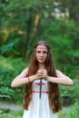 A young beautiful Slavic girl with long hair and Slavic ethnic dress stands in a summer forest with a ritual dagger in her hands Royalty Free Stock Photo