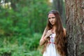 A young beautiful Slavic girl with long hair and Slavic ethnic dress stands in a summer forest with a ritual dagger in her hands Royalty Free Stock Photo