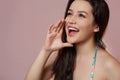 A young beautiful slender Asian girl in a blue swimsuit covered up in surprise, in admiration, in delight .  on a pink Royalty Free Stock Photo