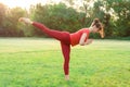 A young beautiful slender girl stands on one leg in a warrior pose. Woman is practicing yoga and stretching. Royalty Free Stock Photo