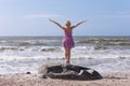 Young beautiful slim girl standing on the beach on a sunny summer day, a strong wind on the sea Royalty Free Stock Photo