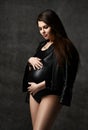 Young beautiful slim pregnant woman with long hair in posing on black background. Pregnancy motherhood, new born life expectation Royalty Free Stock Photo