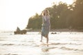 Young beautiful slim woman with short light hair wearing green summer dress walking at sea coast at sunset Royalty Free Stock Photo