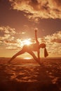 Young beautiful slim woman silhouette practices yoga on the beach at sunset. Yoga at sunrise Royalty Free Stock Photo