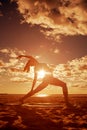 Young beautiful slim woman silhouette practices yoga on the beach at sunset. Yoga at sunrise Royalty Free Stock Photo