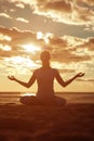 Young beautiful slim woman silhouette practices yoga on the beach at sunset. Yoga at sunrise Royalty Free Stock Photo