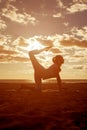 Young beautiful slim woman silhouette practices yoga on the beach at sunset. Yoga at sunrise Royalty Free Stock Photo