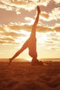 Young beautiful slim woman silhouette practices yoga on the beach at sunrise. Yoga at sunset Royalty Free Stock Photo