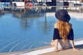 Young beautiful smile girl in black fashion hat, red lips and long hair, posing near pool beackground of palms.