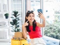 Young beautiful smiling Asian woman holding smart mobile phone and make selfie by camera. Royalty Free Stock Photo