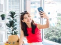 Young beautiful smiling Asian woman holding smart mobile phone and make selfie by camera. Royalty Free Stock Photo