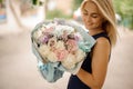 Young beautiful smiling blond woman holds bouquet in her hands and looks at it Royalty Free Stock Photo