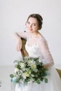 Young beautiful smiling bride with bouquet of flowers sitting in a chair , close-up Royalty Free Stock Photo