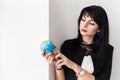 Young Beautiful smiling brunette woman dressed in black business suit holding a globe of the planet Earth