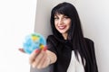 Young Beautiful smiling brunette woman dressed in black business suit holding a globe of the planet Earth