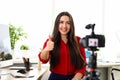 Young woman sitting in office opposite camera and showing good luck thumb finger up Royalty Free Stock Photo