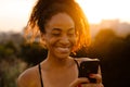 Young beautiful smiling curly african woman holding and using phone Royalty Free Stock Photo